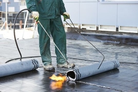 Rolling out bitumen torch down flat roofing Vaughan